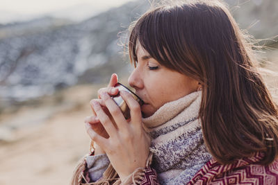 Close-up of woman drinking coffee in container during winter