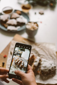 Baker takes a photo of the baked christmas stollen, on a mobile phone