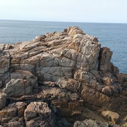 Rock formation by sea against clear sky