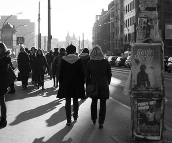 Rear view of people walking on city street