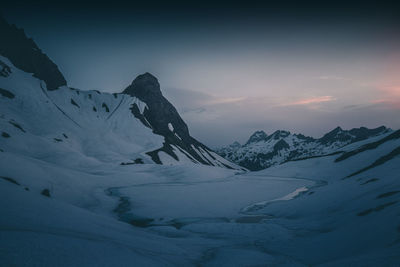 Scenic view of snowcapped mountains against sky during sunset