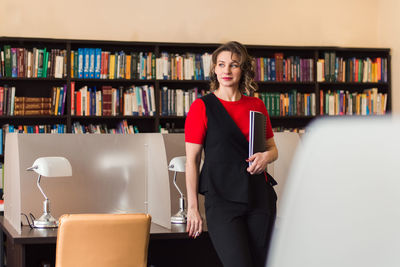 Professional woman educator or manager posing at public library of high school or college