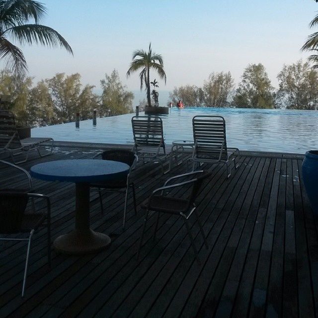 tree, water, wood - material, bench, empty, clear sky, absence, chair, railing, table, tranquility, pier, tranquil scene, lake, sky, nature, wood, wooden, sea, sunlight