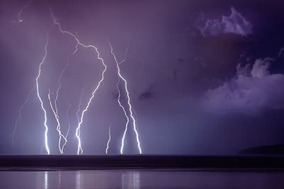 Lightning over sea against storm clouds