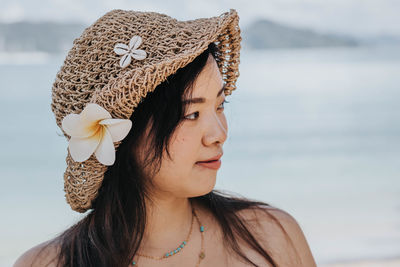 Close-up of woman wearing hat looking away against sea