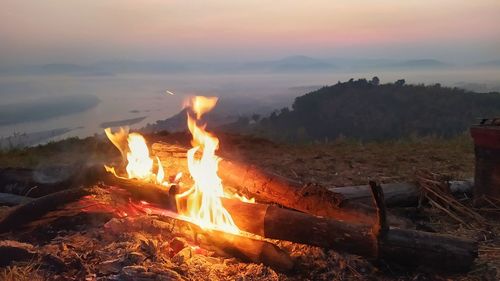 Bonfire on field against sky at sunset