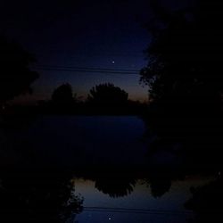 Silhouette of trees and lake at sunset