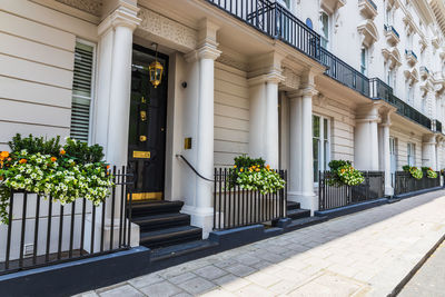 Elegant georgian style townhouses in london with white facades, black doors, and floral decor