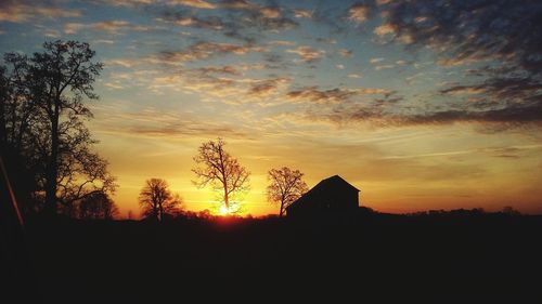 Silhouette houses against sky during sunset