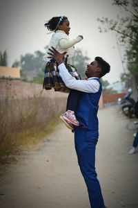 Side view of young man holding sister on road