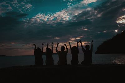 Silhouette people on beach against sky during sunset