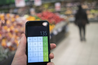 Hand holding calculator in supermarket