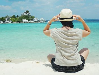 Rear view of woman in hat relaxing at beach