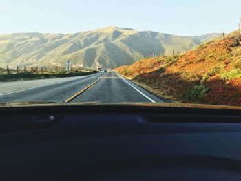 Road seen through car windshield against sky