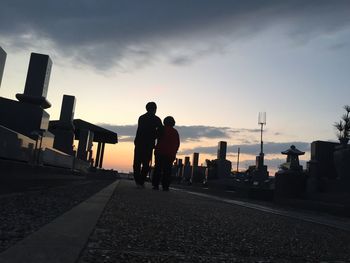 People walking on road against cloudy sky