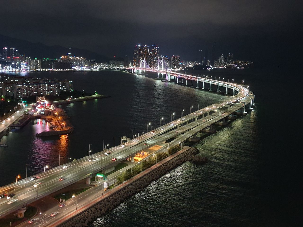 HIGH ANGLE VIEW OF ILLUMINATED BRIDGE OVER RIVER IN CITY