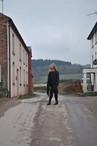 Woman standing on road amidst houses