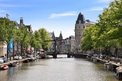 Bridge over canal amidst buildings in city against sky