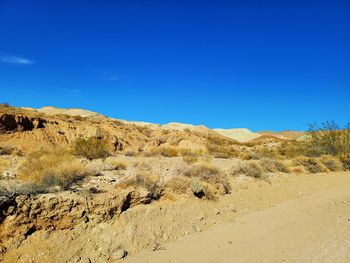 Scenic view of arid landscape against clear blue sky