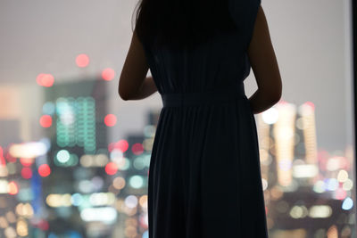 Rear view of woman standing against illuminated lights