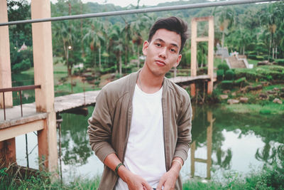 Portrait of young man standing against railing