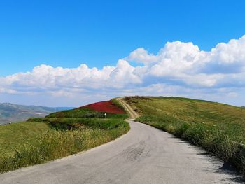 Road amidst green landscape against sky