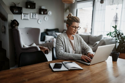 Woman using laptop on table while sitting at home