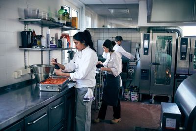 Female chef seasoning tomatoes while standing at kitchen counter