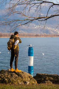 Rear view of man standing on rock against sea