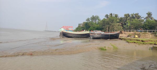 Boat moored on beach against sky