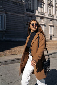 Young woman wearing sunglasses standing on street in city