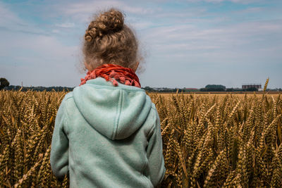 Rear view of woman standing in wheat field against sky