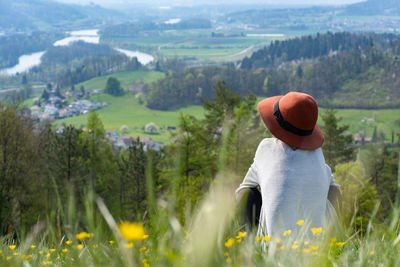 Rear view of woman wearing hat standing on mountain