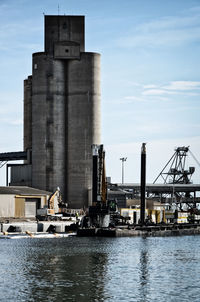 Factory by sea against sky