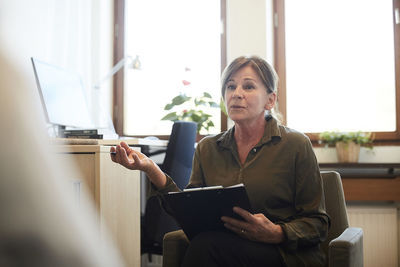 Confident senior counselor discussing with patient at workshop