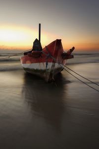 Boat in sea against sky during sunset