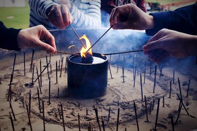 Cropped hands burning incense sticks