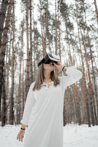 Woman wearing virtual reality simulator against trees outdoors