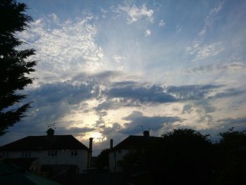 Silhouette houses against cloudy sky