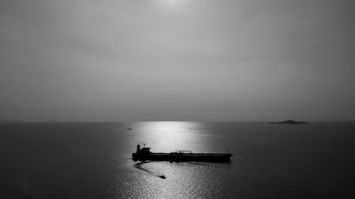 Black and white silhouette shipping oil float in sea aerial view horizon background