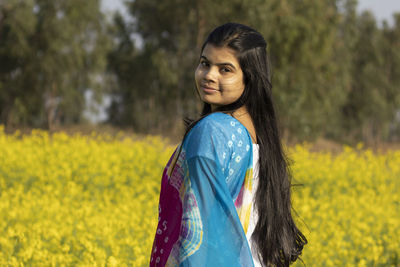 Portrait of smiling young woman standing on field