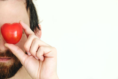 Close-up of man holding apple against white background