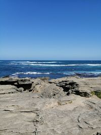 Scenic view of beach against clear blue sky