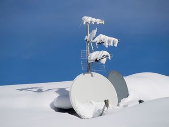 White umbrella on snow against clear blue sky