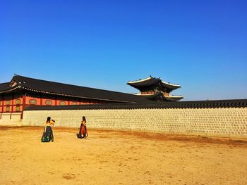 People on built structure against clear blue sky