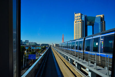 Metro train in city against clear sky seen from window