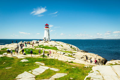 Lighthouse by sea against blue sky