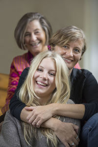 Portrait of three generation females sitting in a row at home