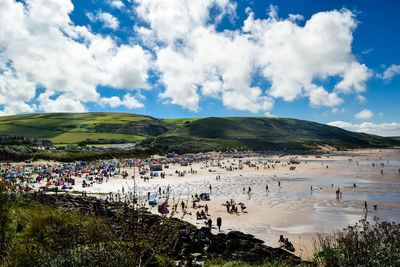 Panoramic view of people on beach against cloudy blue sky in woolacombe, devon