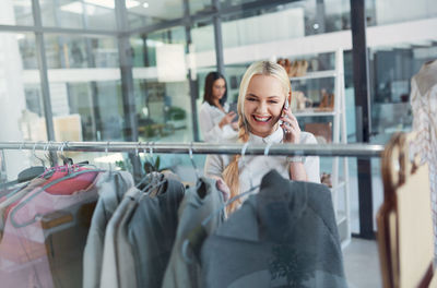 A young woman talking on a phone, shopping in a clothing store. business owner or customer in a shop